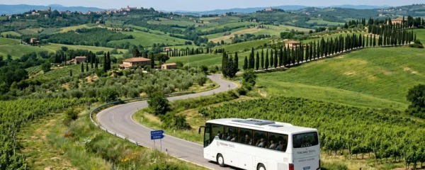 A modern white intercity bus driving along a scenic Tuscan road lined with cypress trees under bright afternoon sunlight